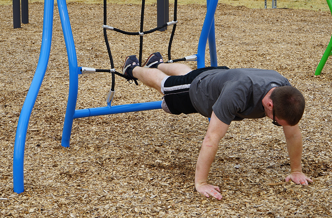 Man planking using playground equipment